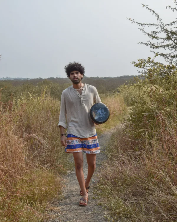 Man in a beige kurta and Whats Down Cleopatra blue-and-orange printed boxers walking through dry grass