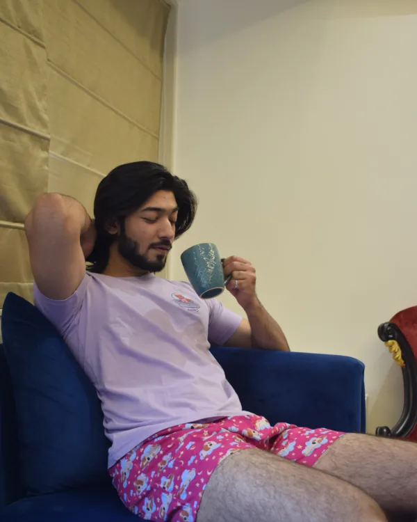 Man in a pink tee and Whats Down pink printed boxers on a sofa with a mug