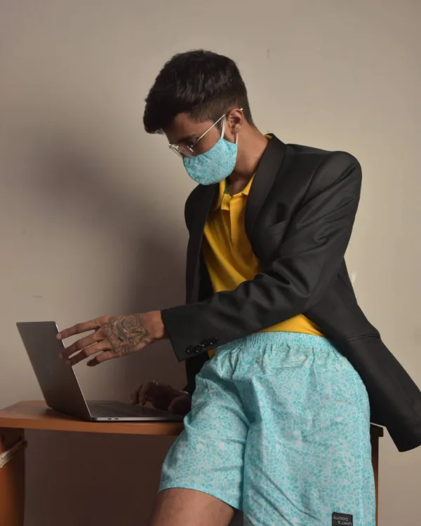 Man in a blazer, Whats Down printed face mask and light-blue printed boxers working on a laptop