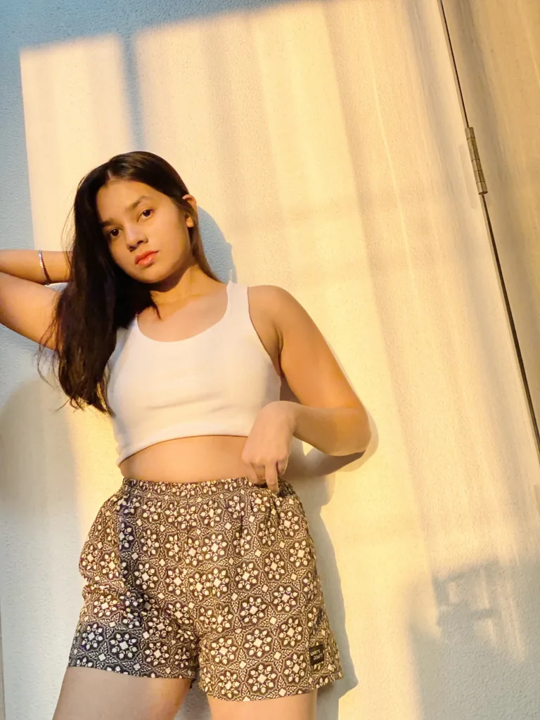 Woman in a white top and Whats Down grey-brown printed boxers in a sunlit room standing