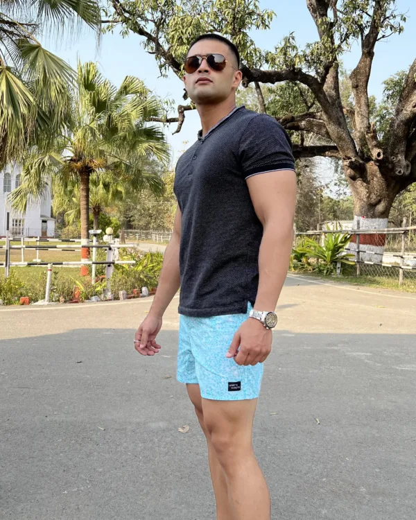 Man in a black tee and Whats Down light-blue printed boxers on a tree-lined road in sunglasses
