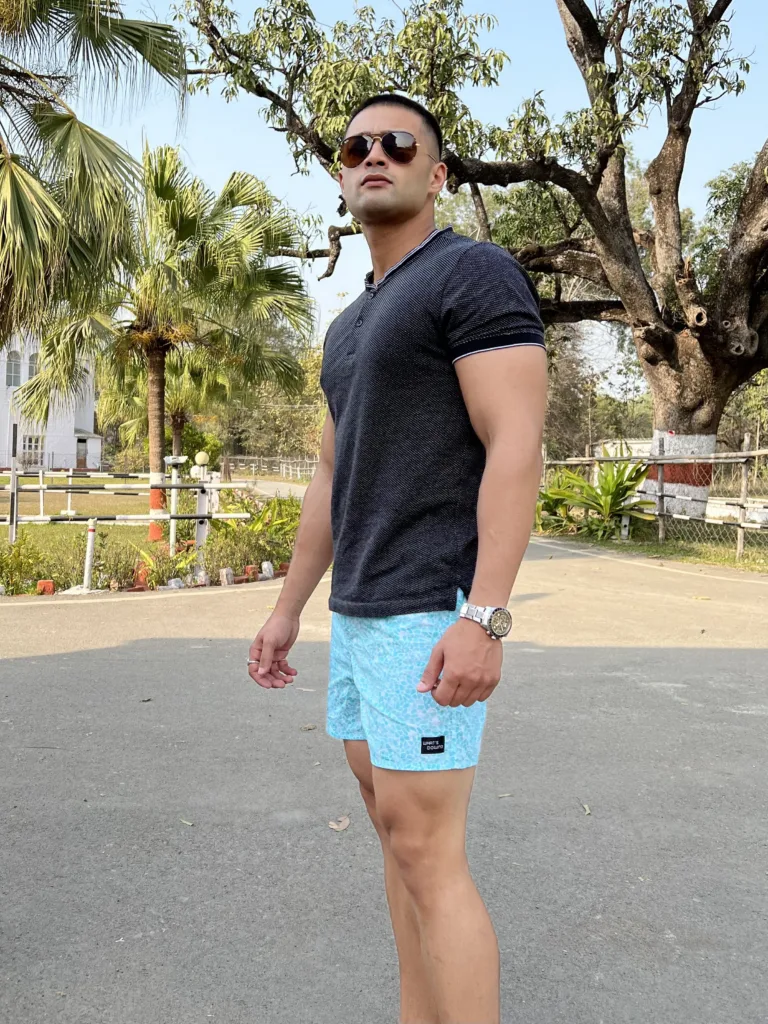 Man in a black tee and Whats Down light-blue printed boxers on a tree-lined road in sunglasses