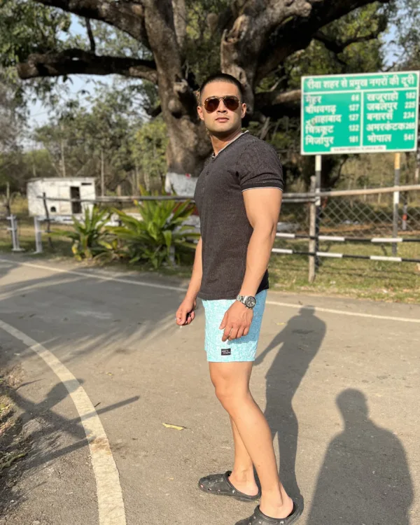 Man in a black tee and Whats Down light-blue printed boxers on a tree-lined road walking