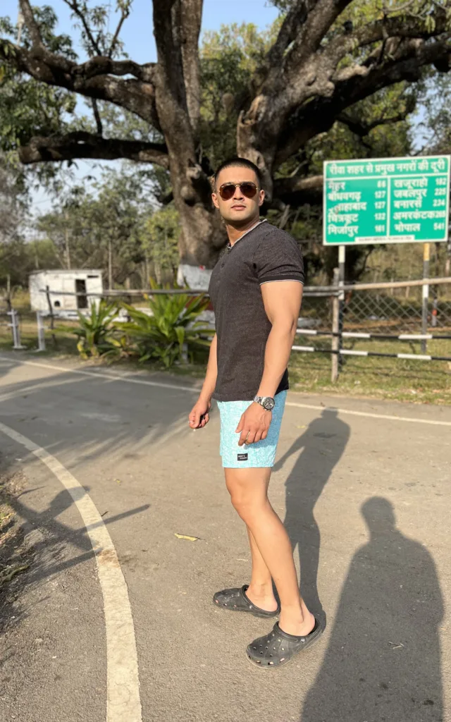 Man in a black tee and Whats Down light-blue printed boxers on a tree-lined road walking