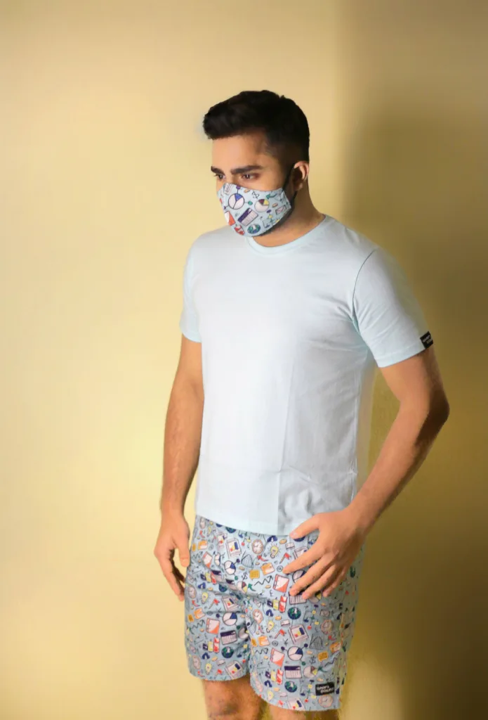 Man in a white tee and Whats Down black multicolour printed boxers adjusting a printed face mask