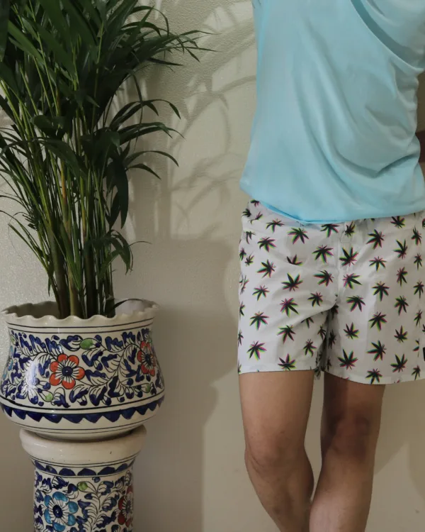 Man in a light-blue tee and Whats Down white printed boxers beside a palm plant. Waistband detail