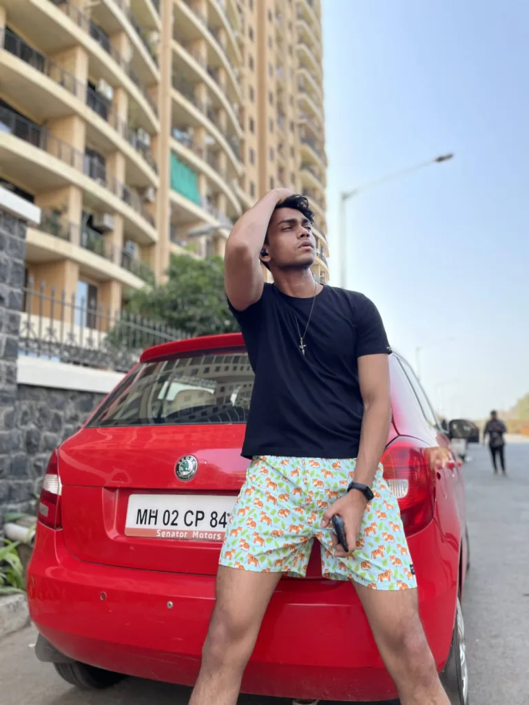Man in a tee and Whats Down printed cotton boxers leaning on a red car in the city