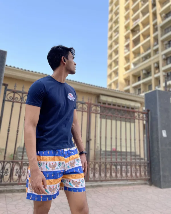 Man in a tee and Whats Down printed cotton boxers walking past a stone wall and tower