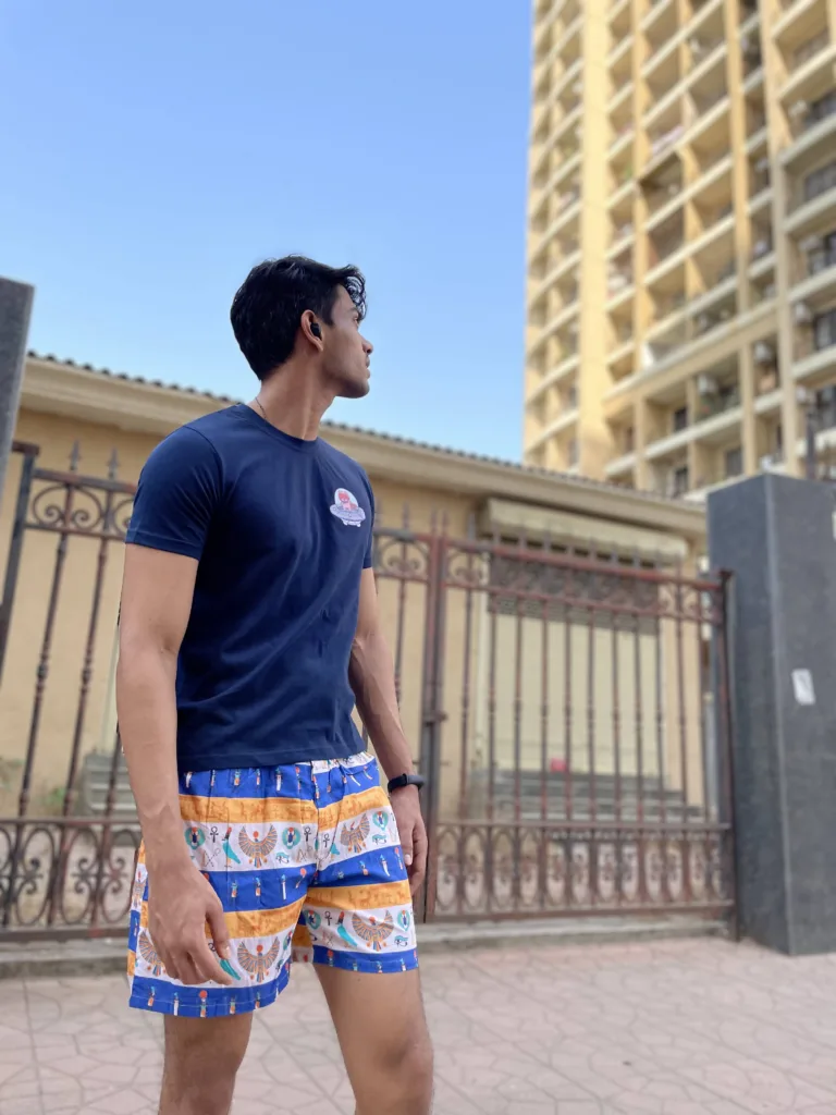 Man in a tee and Whats Down printed cotton boxers walking past a stone wall and tower