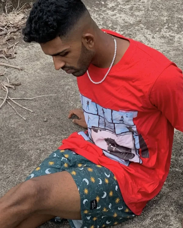 Man in a red tee and Whats Down green printed boxers sitting on rocks