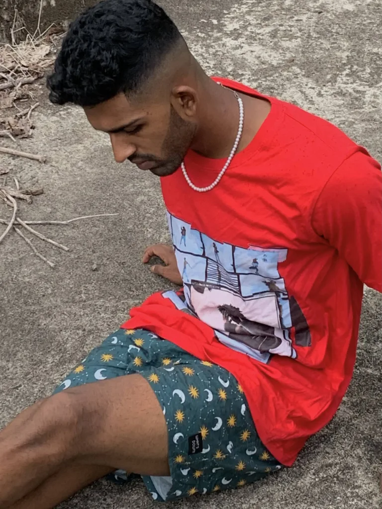 Man in a red tee and Whats Down green printed boxers sitting on rocks