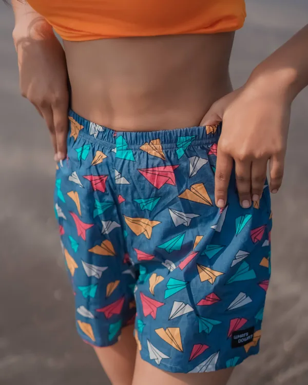 Woman in an orange crop top and Whats Down teal ice-cream printed boxers on the beach. Waistband detail