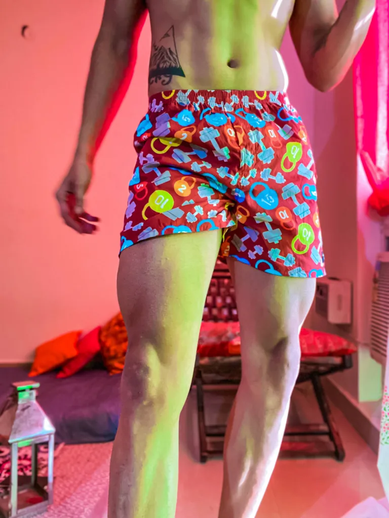 Man in Whats Down navy pop-print boxers in a neon-lit room standing
