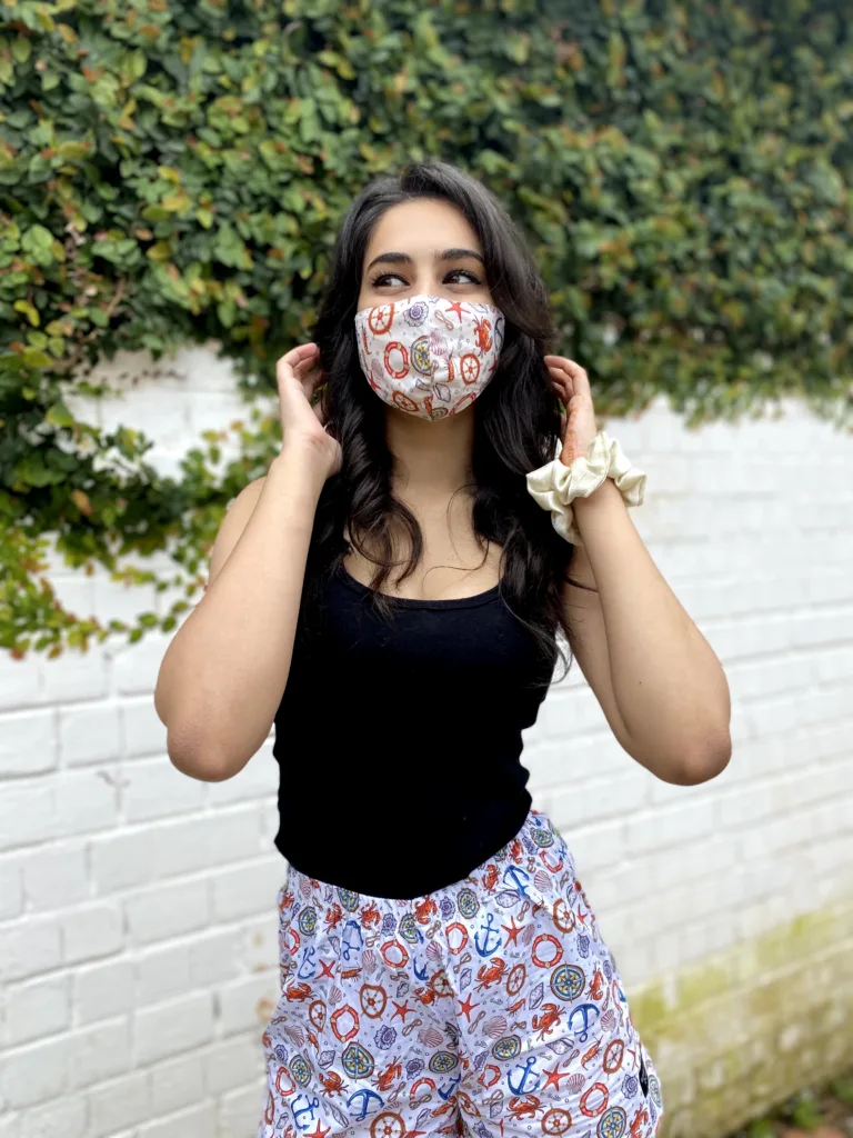 Woman in a Whats Down printed face mask and white floral printed boxers by an ivy wall