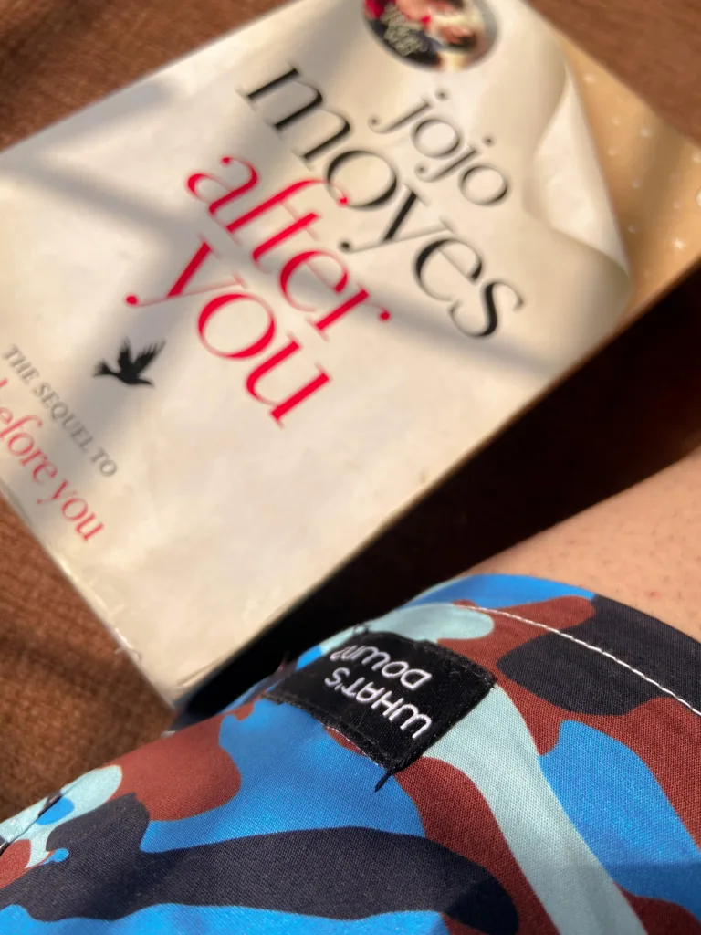 Man reading on the bed in Whats Down Blue Camo printed boxers. Photo 1