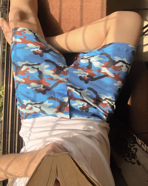 Man reading on the bed in Whats Down Blue Camo printed boxers. Photo 2