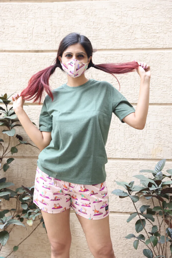 Women in pastel tees and Whats Down pink and red printed boxers on a plant-filled terrace hand on hip