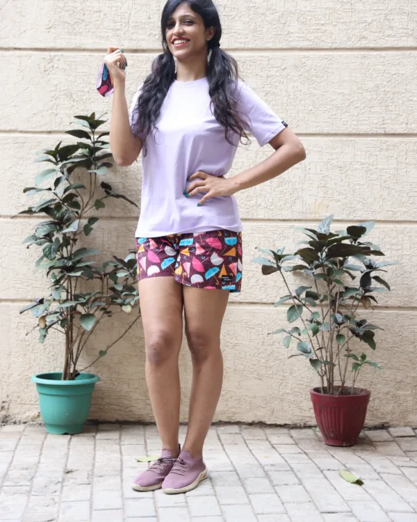 Women in pastel tees and Whats Down pink and red printed boxers on a plant-filled terrace laughing