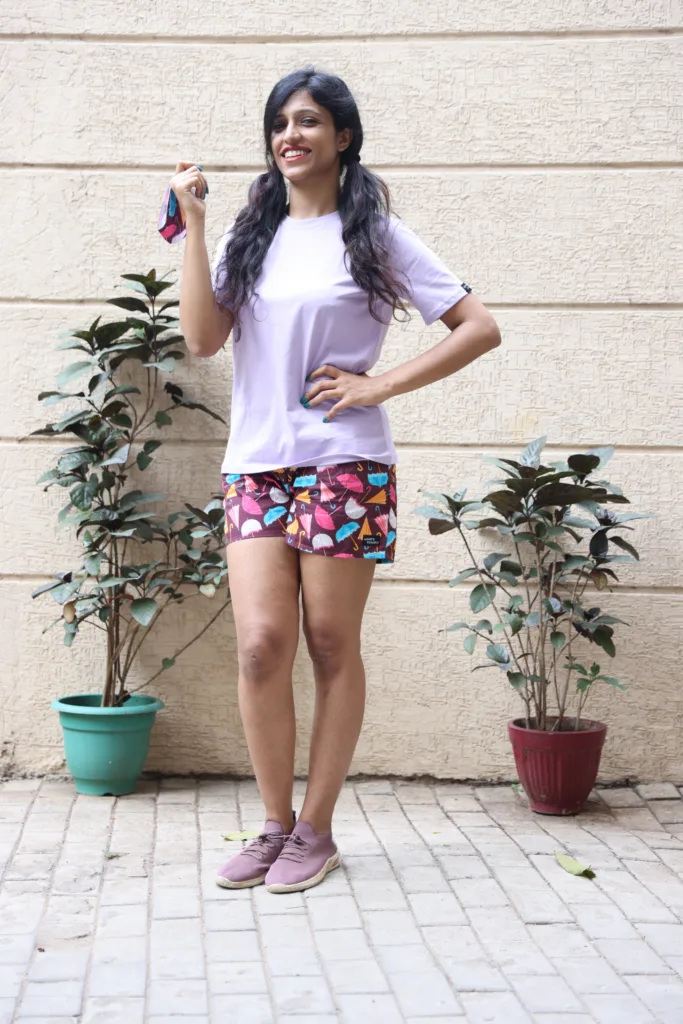 Women in pastel tees and Whats Down pink and red printed boxers on a plant-filled terrace laughing