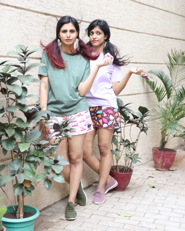 Women in pastel tees and Whats Down pink and red printed boxers on a plant-filled terrace together