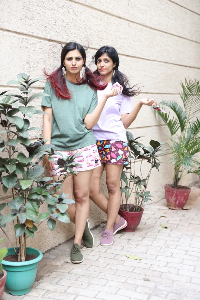 Women in pastel tees and Whats Down pink and red printed boxers on a plant-filled terrace together