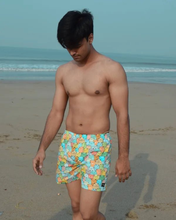 Man in Whats Down yellow-and-blue printed boxers on the beach walking on the sand