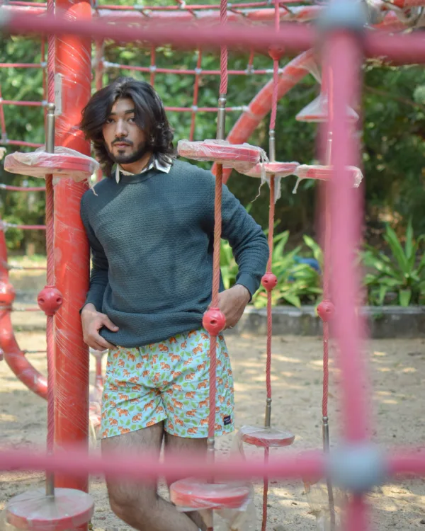 Man in a green sweater and Whats Down Green Sher Khan printed boxers at a playground behind the climbing frame