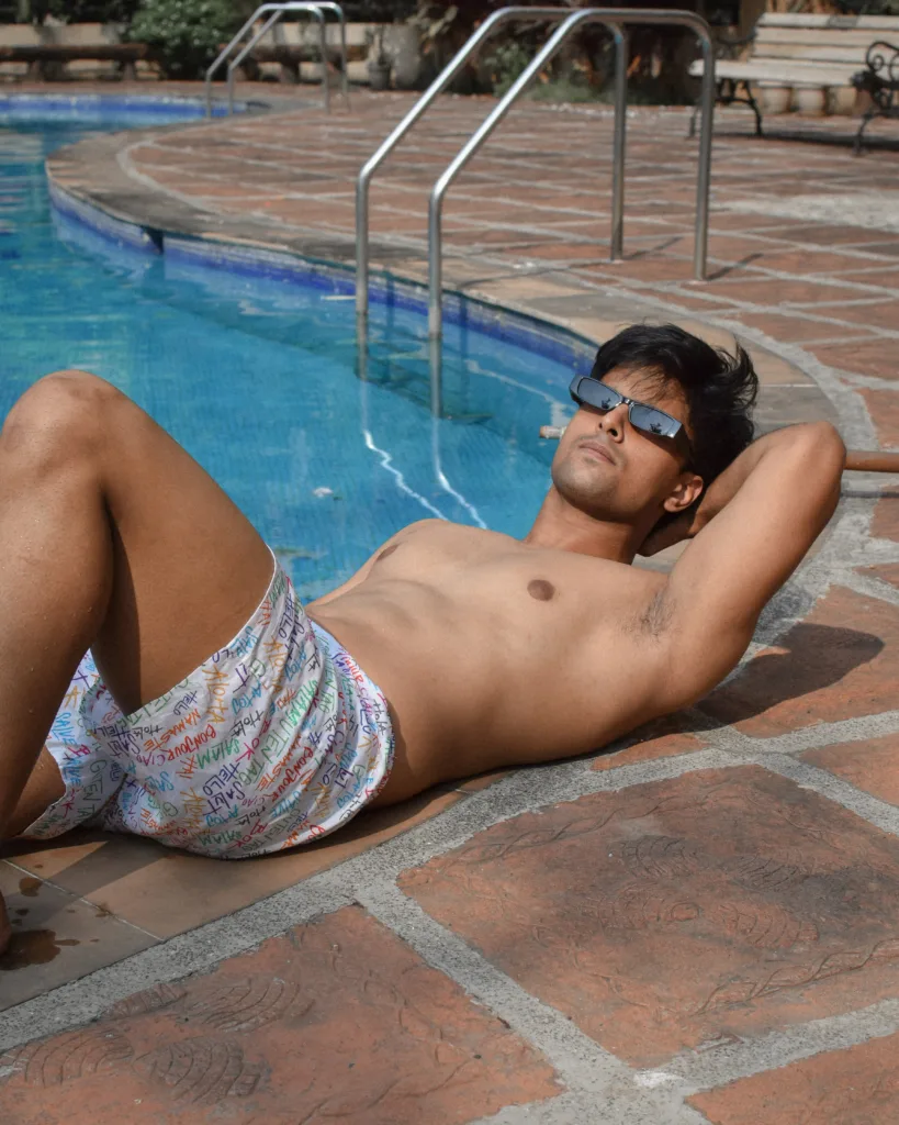 Man in Whats Down white printed boxers by the pool lying on the edge