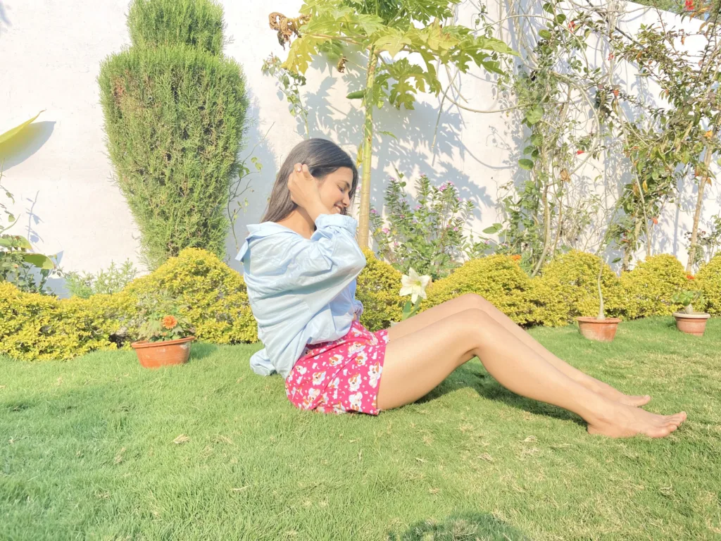 Woman in a blue shirt and Whats Down pink printed boxers on the grass sitting up in the garden
